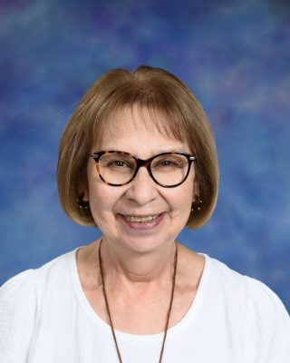 Smiling woman with glasses against a blue background.