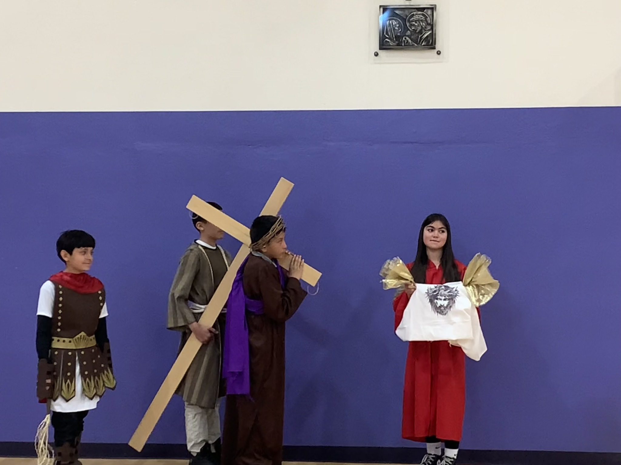 Children perform a scene from the crucifixion with a cross and a crown of thorns.