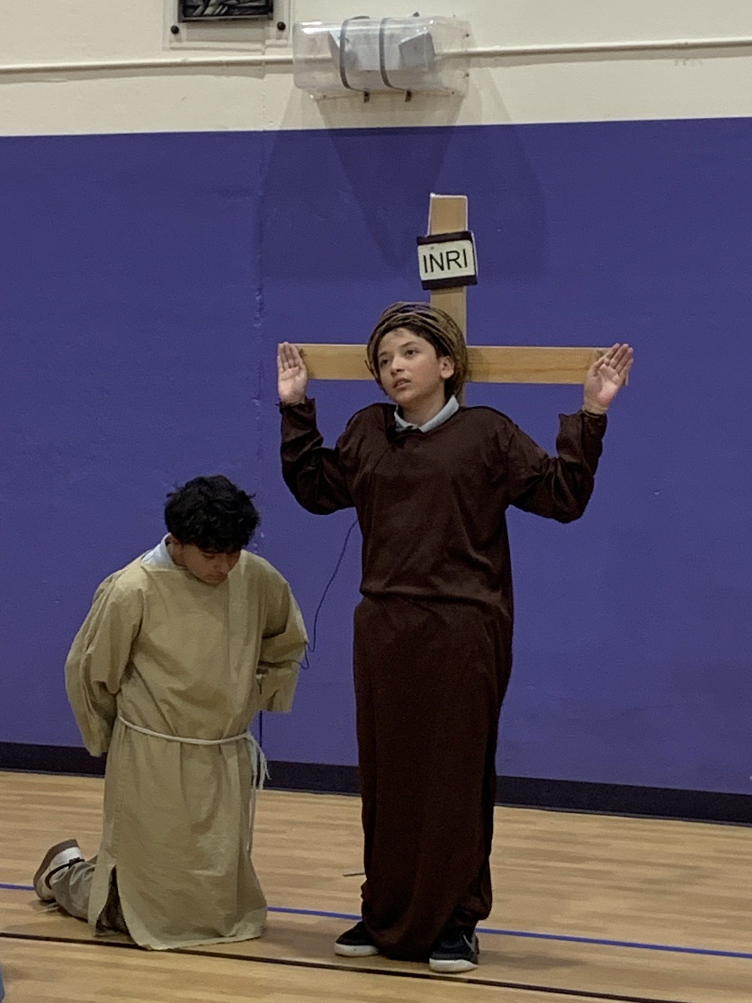 Two individuals performing a dramatic scene with one on a cross.
