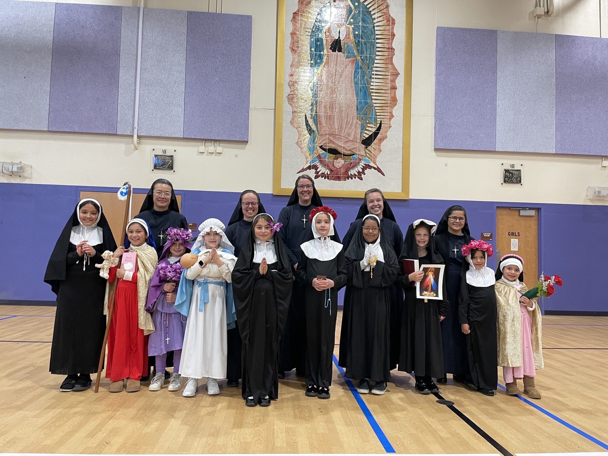 Group of nuns and children in religious attire posing indoors.