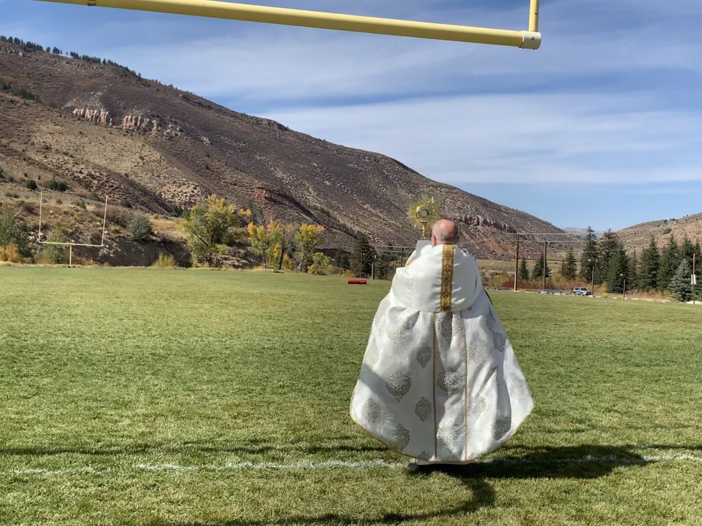 Person in a white robe walking on a football field under a goalpost.