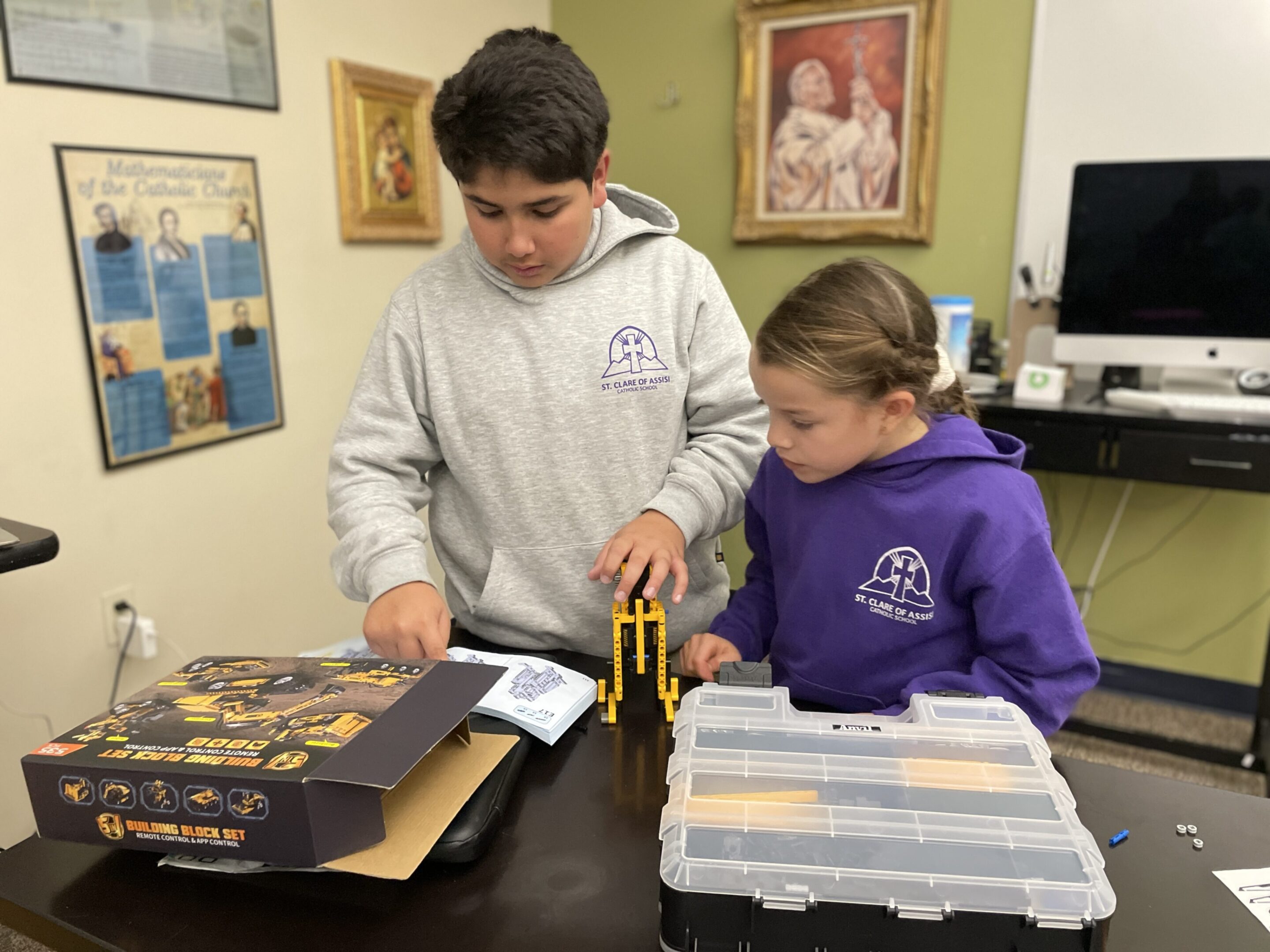 Two children assembling a mechanical project at a table.