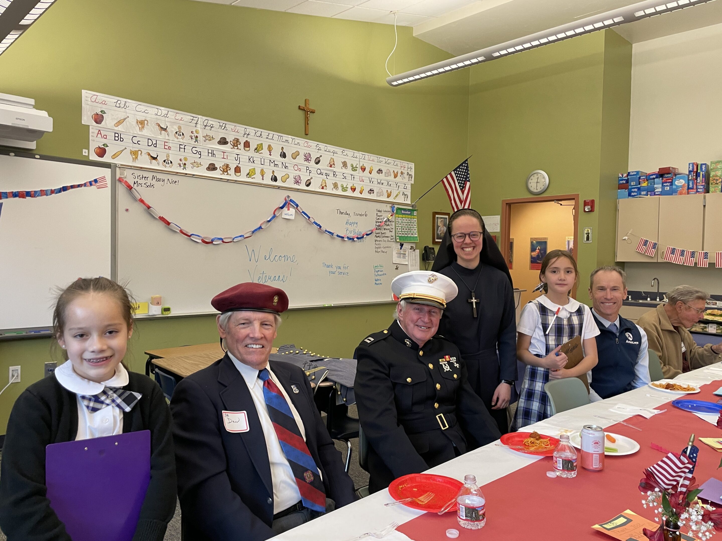 Children and veterans sharing smiles at a decorated table.