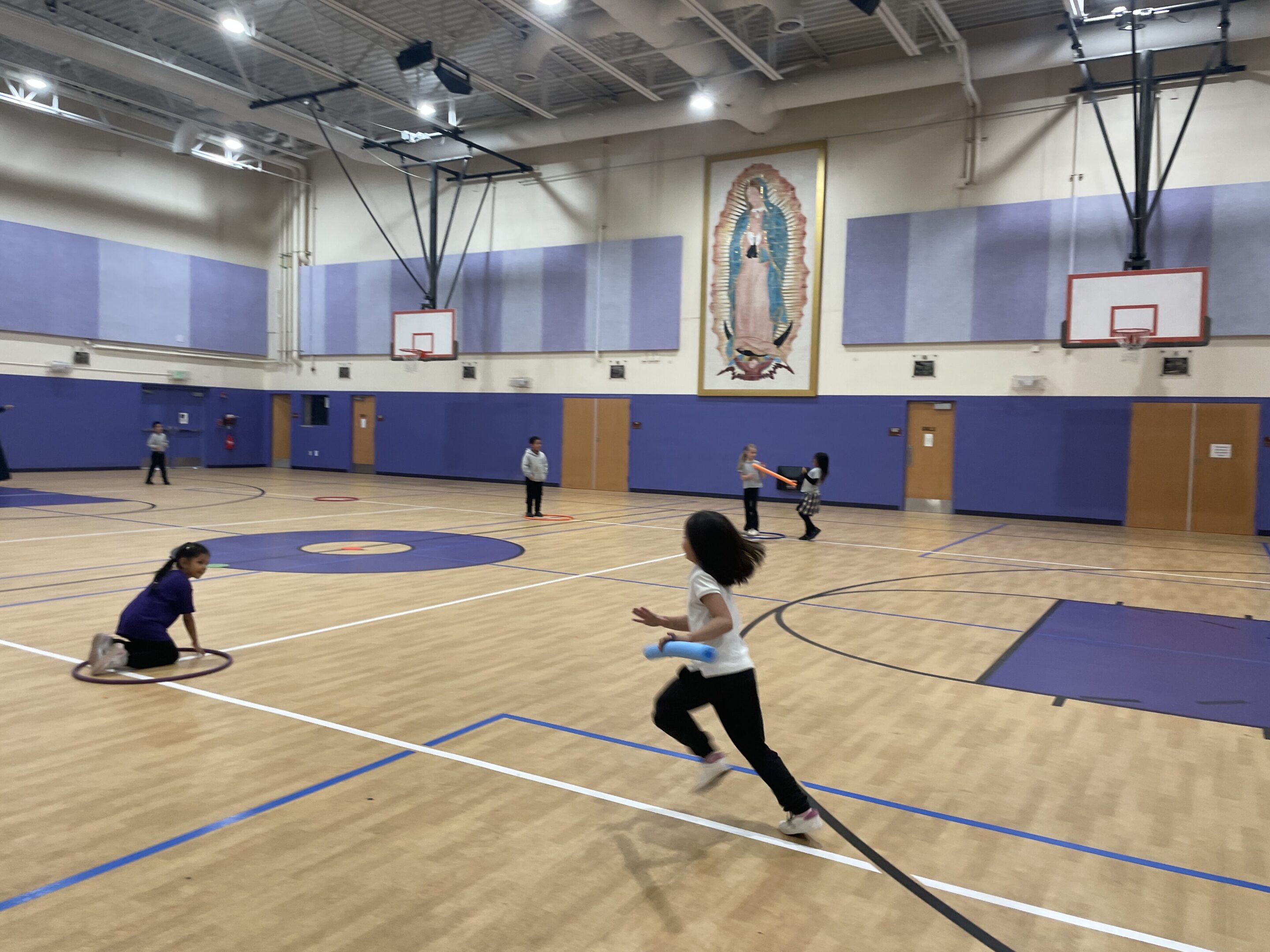 Children playing basketball in an indoor gym.