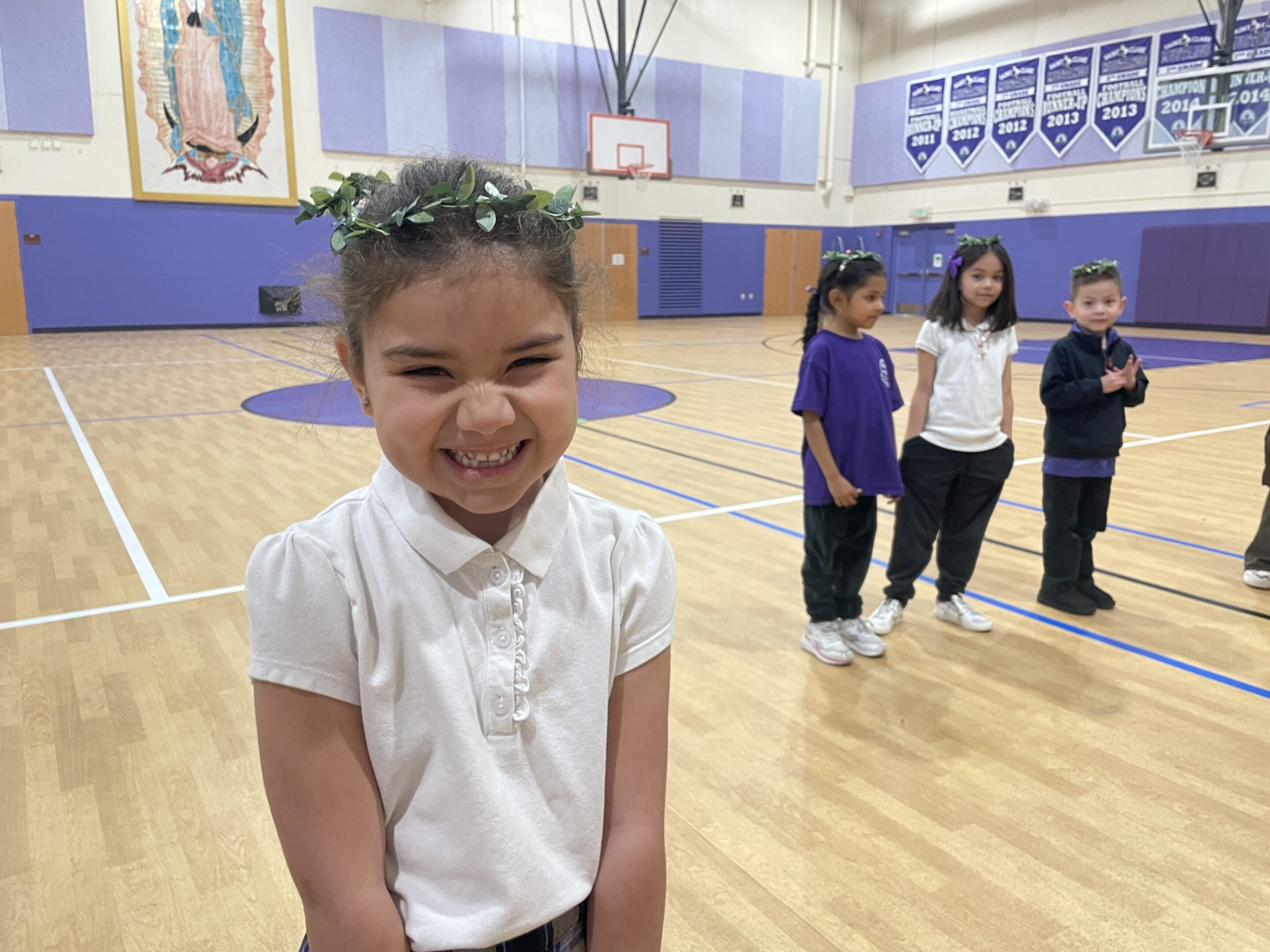 Smiling girl wearing a flower crown in a gymnasium.