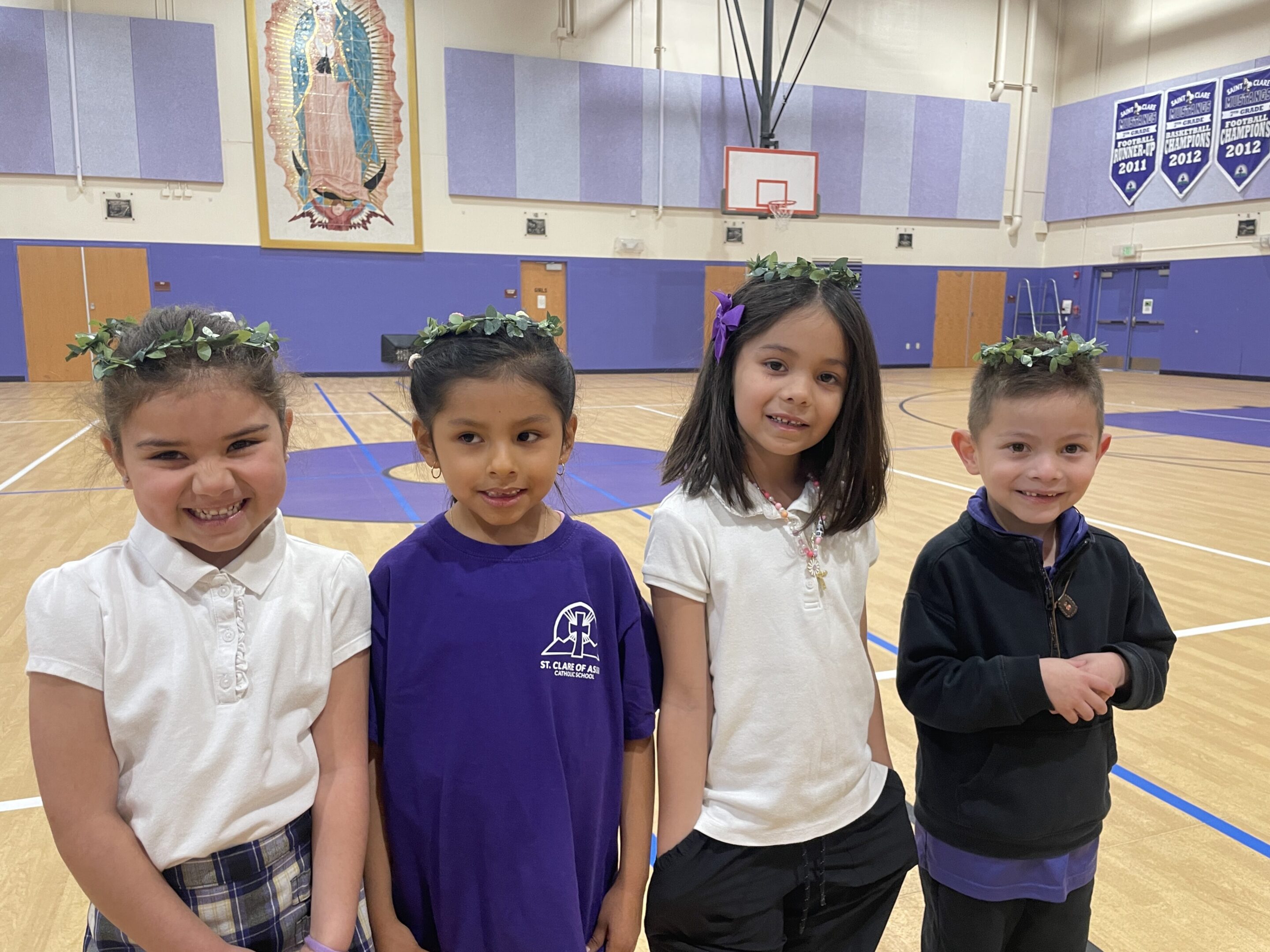Four kids smiling inside a gymnasium.