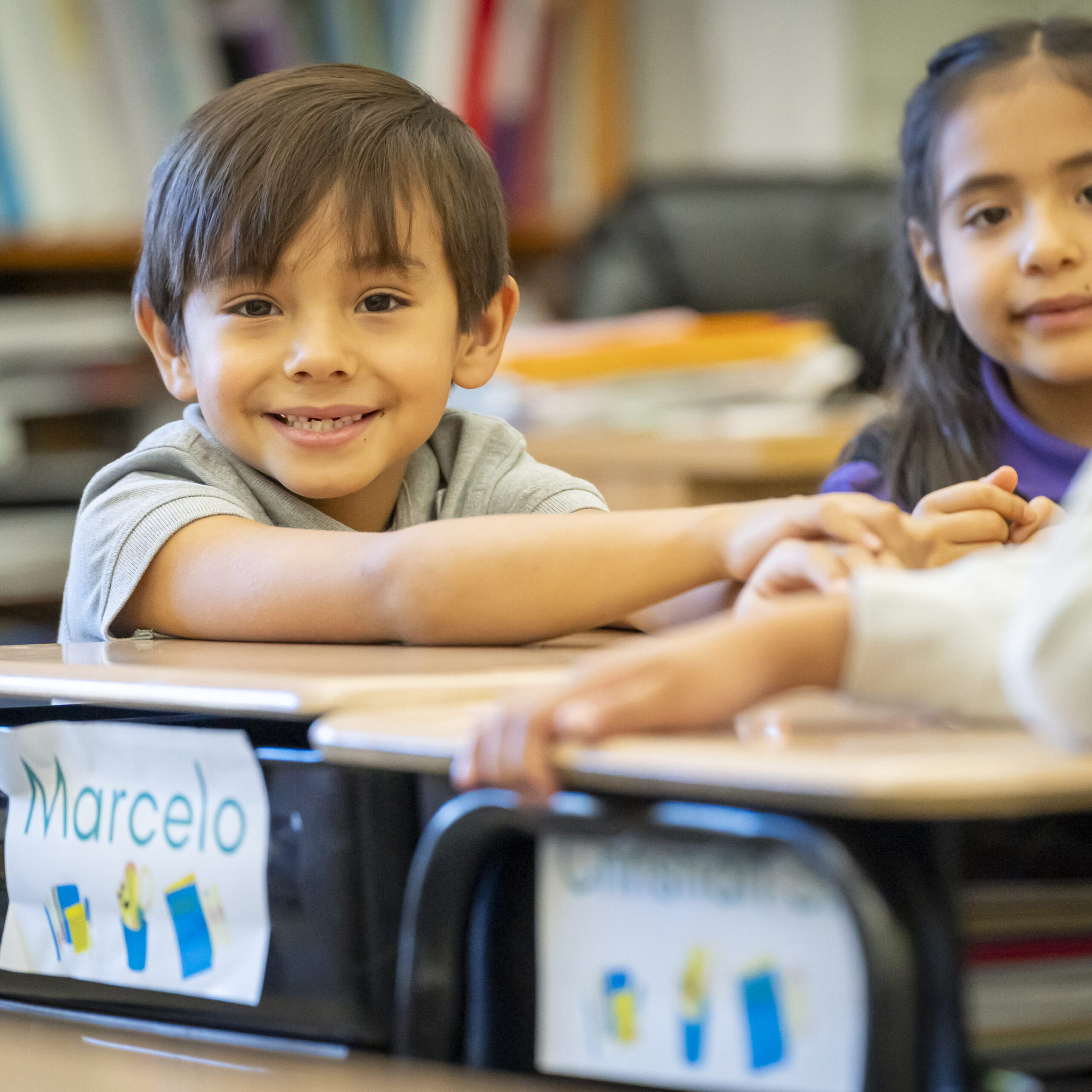 Happy children sitting at their desks in a classroom.